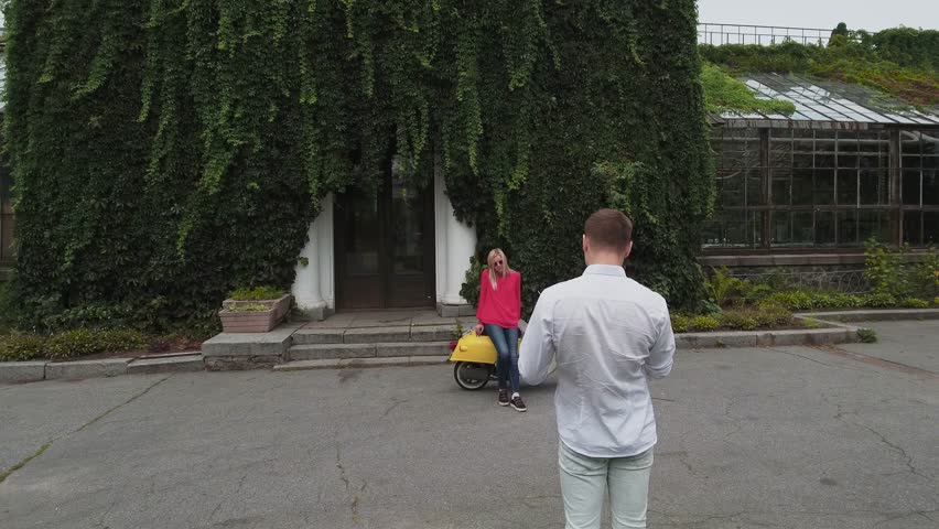 Guy takes a picture of a girl. Shot on drone