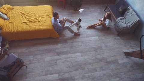 Beautiful young married couple is playing with a dog at home. Angle from above. Slow motion