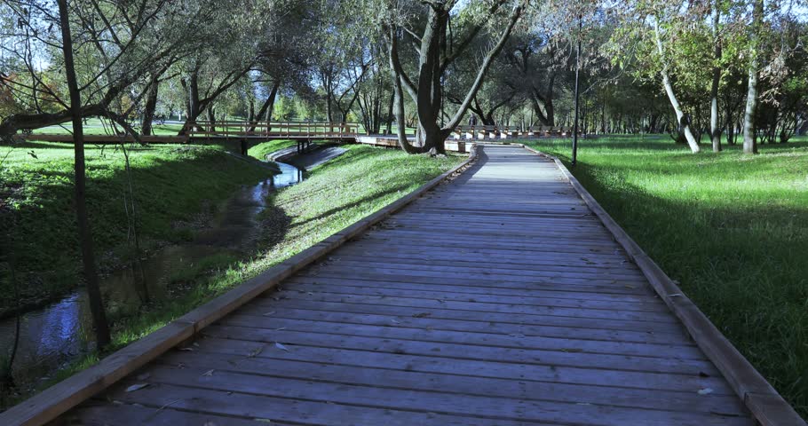 Wooden walkway in the light of the morning sun in the city park of South Butovo
