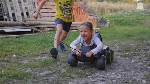 Slow motion group of children playing, running and riding on toy vehicle outdoor. Mixed gender poor kids plays active games with happy and funny emotions