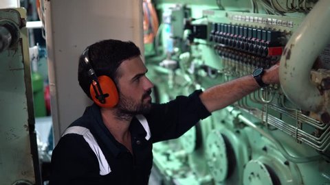 Marine engineer inspecting ship's engine in engine control room ECR. Seamen's work.