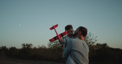 Very charismatic boy with his dad playing together with a airplane outside at nature , closeup , dreaming small boy to be a pilot.