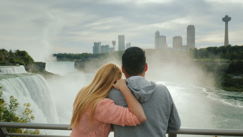 A young multi-ethnic couple admires a beautiful view of the Niagara Falls. Travel in America and Canada
