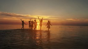 Big crowd of friends having fun at sunset sea beach. Beach vacations concept. Beauty and joyful teenager friends having fun, dancing, spraying over summer sunset. Beach party. Sun flare. Slow motion - Powered by Shutterstock - Get 15% off with code: PIKWIZARD15