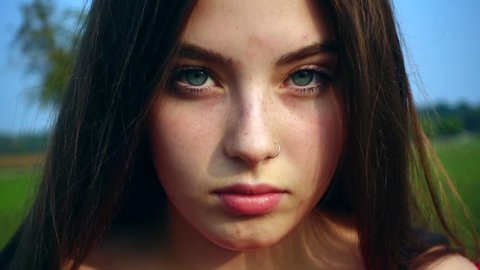 Slow motion close-up portrait of beautiful light-skinned Caucasian teenage girl with freckles and blue eyes with windblown hair