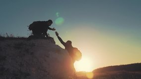 Silhouette of helping hand between two climber. two hikers on top of the mountain, a man helps a man to climb a sheer stone. couple hiking help each other silhouette in mountains with sunlight. - Powered by Shutterstock - Get 15% off with code: PIKWIZARD15