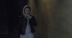 Girl teenager goes at night in the underpass. Young caucasian woman with skateboard in dark underground tunnel. Urban city lifestyle. 4K video shooting by handheld gimbal