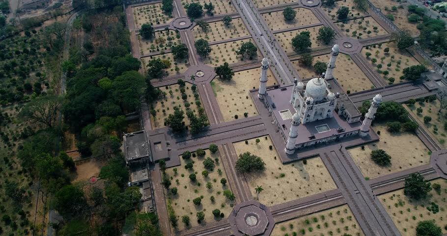 Drone footage of the Marble Mughal mausoleum Bibi Ka Maqbara in Aurangabad, Maharashtra, India, with its huge garden covered in aligned trees mostly young just replanted