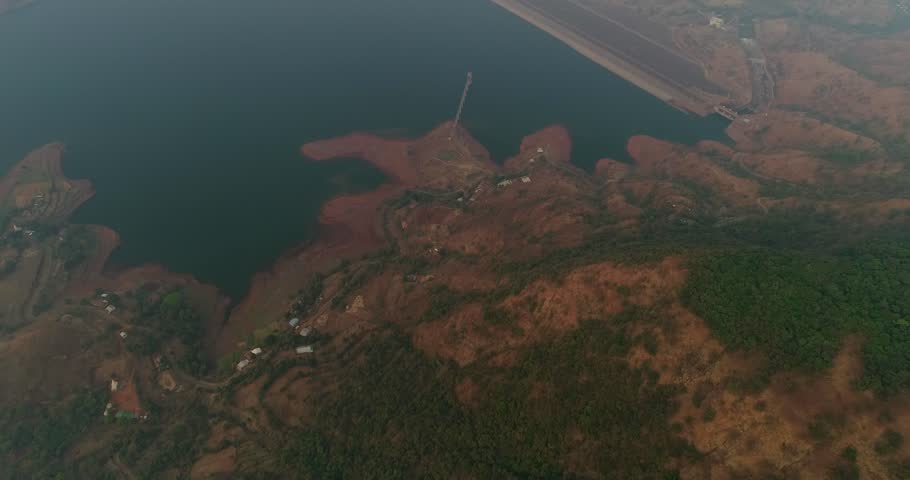 Drone footage around Elephant Head Rock in the surroundings of Mahabaleshwar, Maharashtra, India, with a huge dam closing a river down a valley, a thick fog is present.