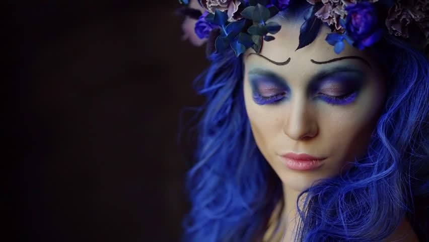 Halloween face art. Portrait of a beautiful woman looking at the camera and smiling, makeup the bride's corpse. Blue accents on hair and eyes, black background Royalty-Free Stock Footage #1018171750