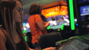 This video shows a young caucasian woman excited as she wins big on a slot machine while gambling at a casino.