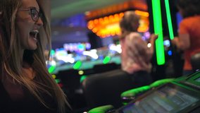 This video shows a young caucasian woman excited as she wins big on a slot machine while gambling at a casino.