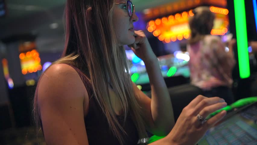 This video shows a young caucasian woman disappointed as she loses money on slot machines while gambling at a casino. Royalty-Free Stock Footage #1018172071