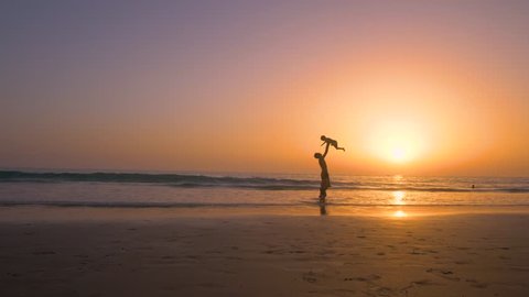 Silhouette of father with two children in the beach at sunset