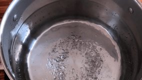 Chef lowers a portion of pasta into a saucepan with boiling water, top view video