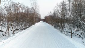 Winter road in the snow, aerial footage. Camera move ahead.