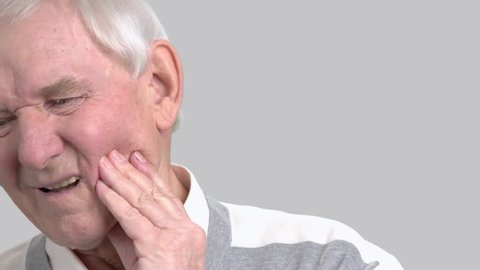 Older man with the tooth pain, toothache. Male senior suffering from terrible toothache on grey background. Sick old man.