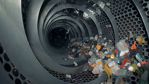 Lots of trash in a recycling center. Recyclable garbage rotates in a special machine at a plant.