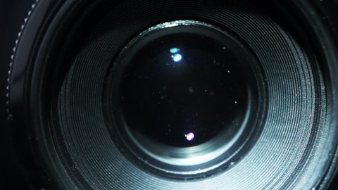 Light is moving over the front of a 35mm camera lens, the camera is taking a picture and you can see the aperture blades 