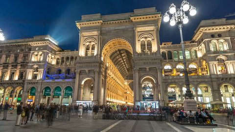 View at night of illuminated Vittorio Emanuele II Gallery time lapse hyperlapse in Milan City, Italy. People walking on Square Piazza Duomo near entrance to shopping centre at night in 4k.