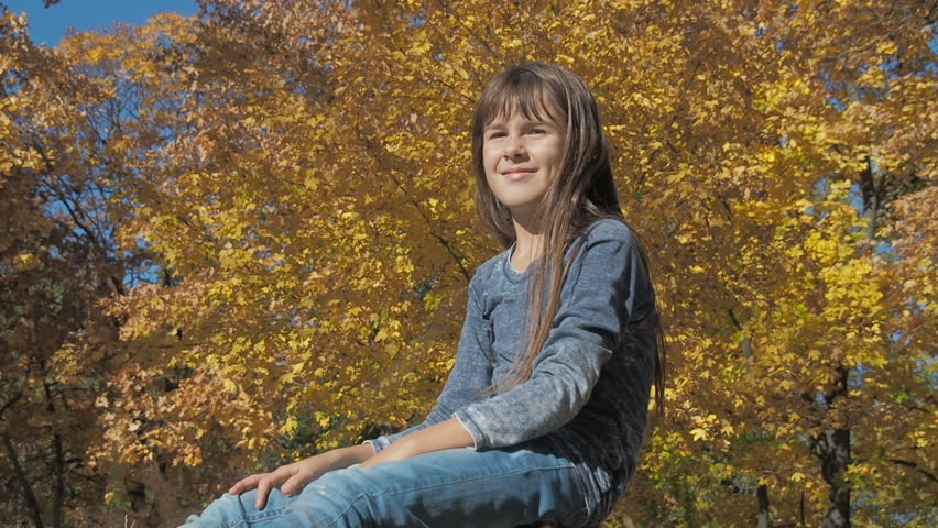 Happy child in autumn park. The girl plays with soap bubbles.