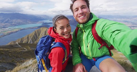 Couple taking selfie video on top of mountain living healthy lifestyle enjoying wanderlust adventure and hiking on Roys Peak Track, Wanaka, Otago, New Zealand.