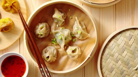 Traditional chinese dumplings served in the wooden bamboo steamer over raw wooden background table. Top View composition.