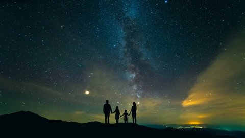 The family standing on the mountain against the starry sky. night time