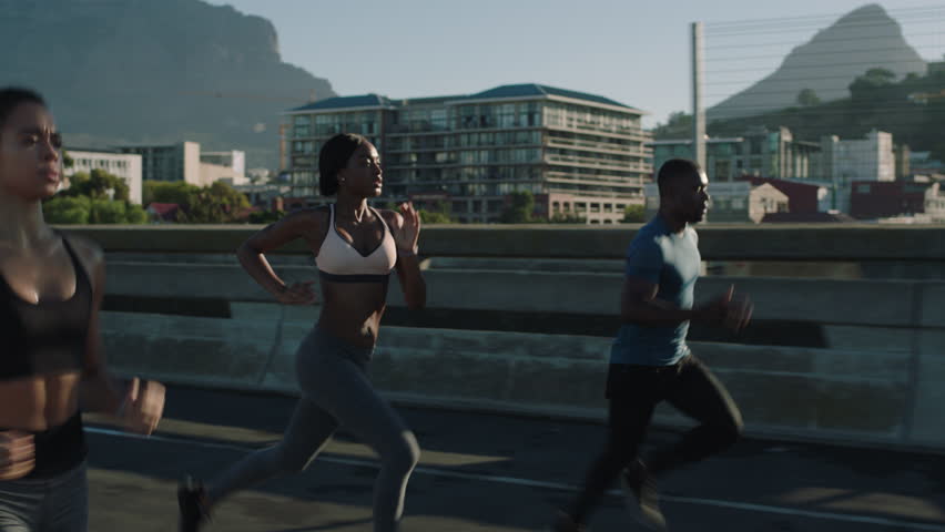 Multi ethnic group athletes running friends enjoying competition race jogging exercising together focused on healthy fitness lifestyle in urban city at sunrise | Shutterstock HD Video #1018213054