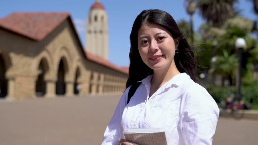 young excellent exchange student looking at camera and smiling confidently in one of the higher educational institutions.