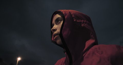 young woman runner ready for intense exercise running training in city at night wearing hood close up