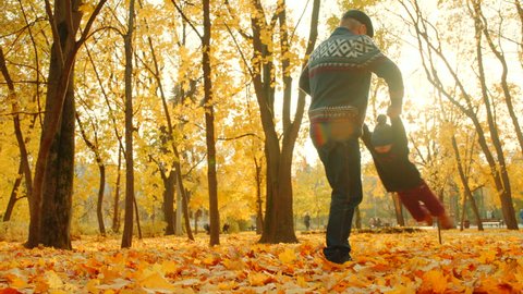 Grandfather playing with his grandson in the autumn park