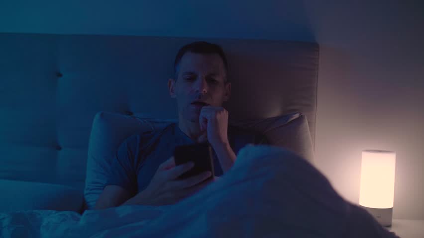 Sleepy guy turns the light off and going to sleep putting down his smartphone beside him Royalty-Free Stock Footage #1018214491