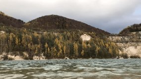 Lake in the mountains and autumn colorful forest with cloudy sky. Time-lapse video