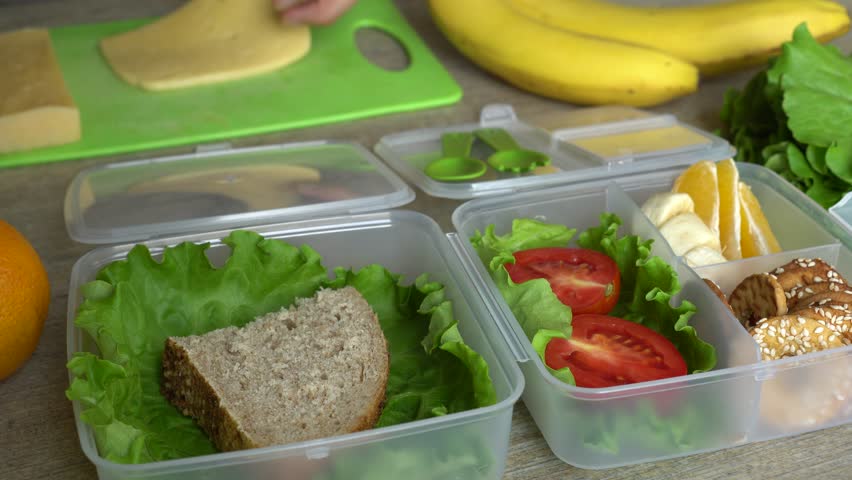 Bento box lunch for back to school and work lunches. Female hands making sandwiches and putting into take away plastic container