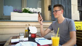 Young teenager chatting on smartphone and drinking beverage in garden
