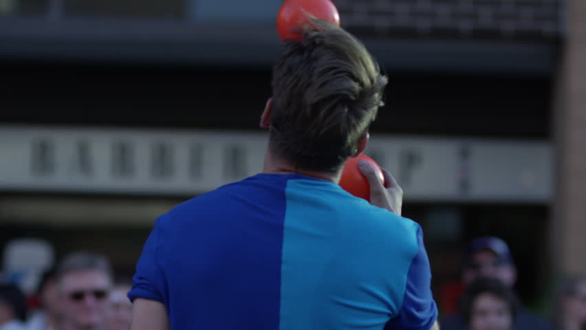 Slow motion juggler doing head trick with balls