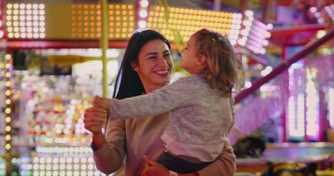 Portrait of a young mother having fun with her daughter at the Lunapark. Concept: Family, happiness, freedom. Shot on RED 8K.