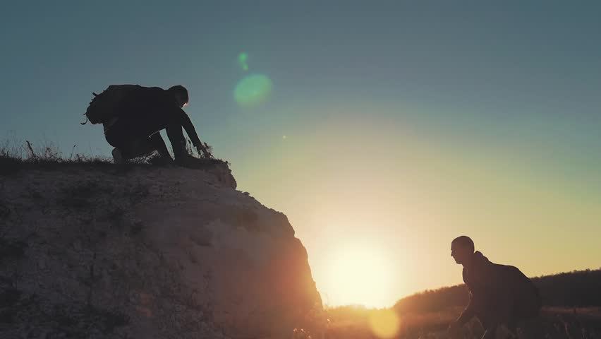Climber helping teammate climb, the man with the backpack reached out a helping hand to his friend. Hiker helping friend while trekking on hill. Tourist man helps someone to climb the mountain. Royalty-Free Stock Footage #1018229182