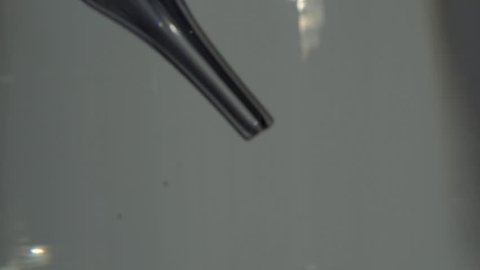 Closeup of liquid drop from laboratory pipette to the water over white background