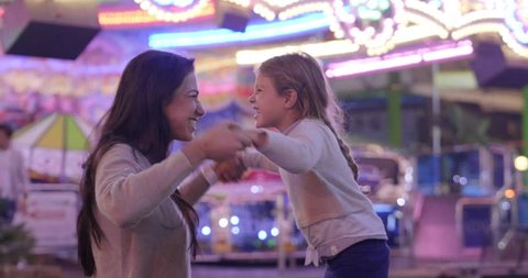 Portrait of a young mother smiling and having fun with her daughter at the Luna Park. Concept: Happiness, freedom, fun, family