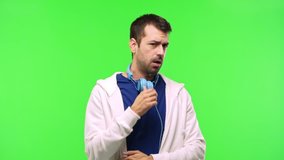 man with sweatshirt and music headphones on green screen chroma key background gaping because have just surprised with a gift