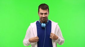 man with sweatshirt and music headphones on green screen chroma key background smiling and showing victory sign with a cheerful face