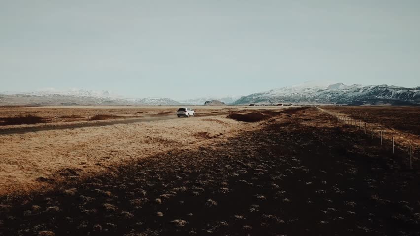 Epic aerial shot of white SUV driving through amazing landscape in Iceland