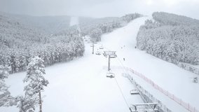 Aerial view of people skiing and ski lift at mountain ski resort.
