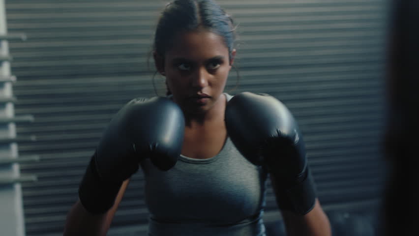 Woman athlete training kickboxing exercise workout punching bag tough female fighter practice boxing in gym enjoying fitness lifestyle