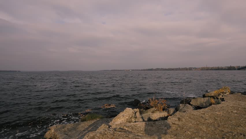 Man traveler in yellow jacket looking at river, rear view, slow motion