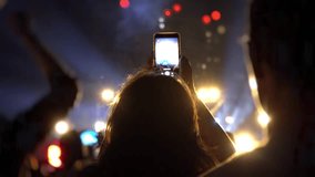Fans are filming a concert on a smartphone. Live broadcast of the concert in social networks. People make photos and videos at the festival. World tour of popular musicians