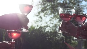 Friends raise wine glasses with pink wine to make a toast. Slow motion 240 fps. Slowmo. High speed camera shot. Full HD 1080p.