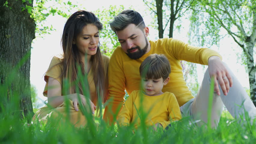 Young family reading outdoors.